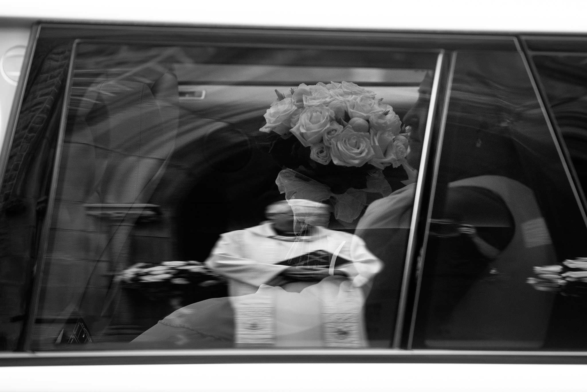 Reflection in the car window of the priest and bride