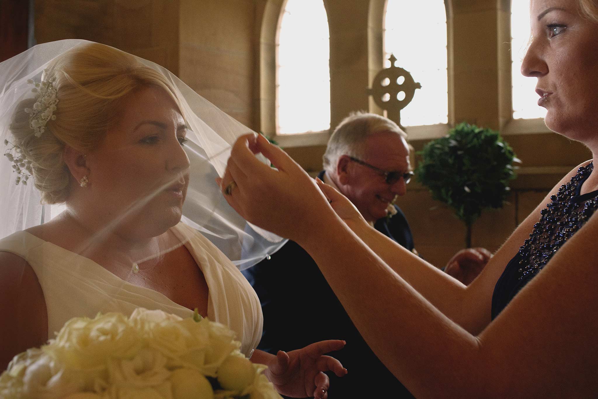 Bridesmaid helping the bride with her veil