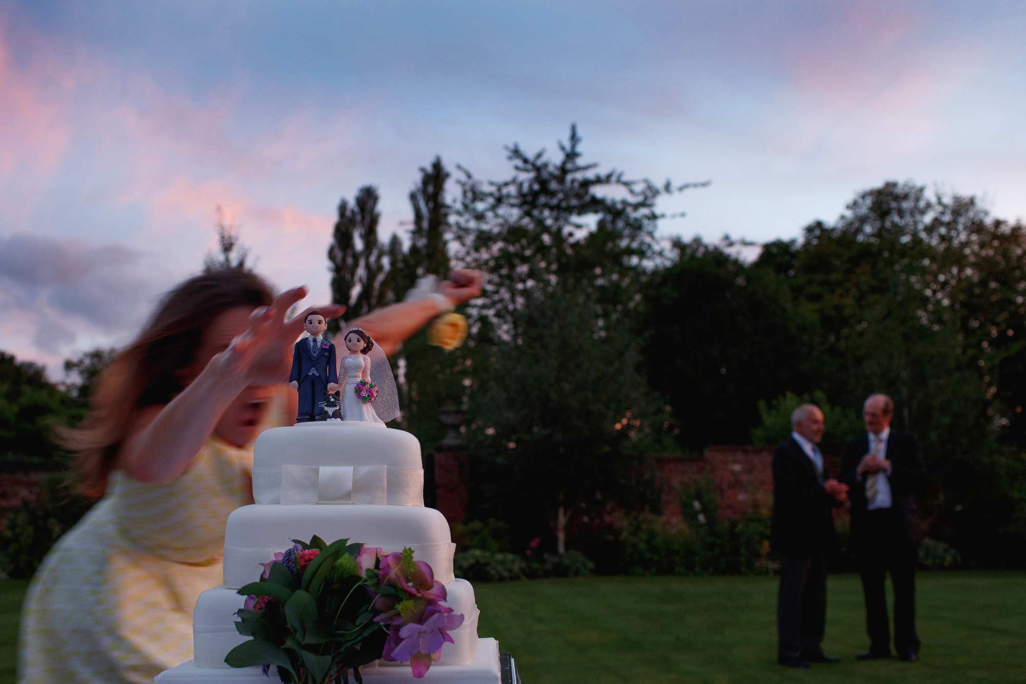 award wining wedding photograph of a wedding cake almost being knocked over