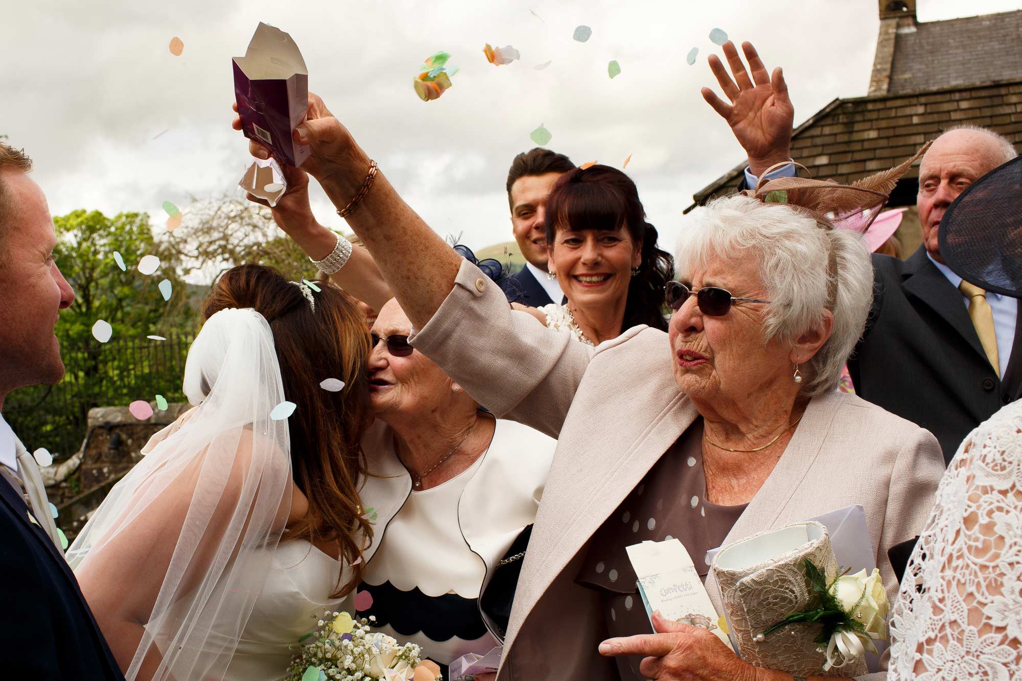 grans kissing bride and groom as guests throw confetti at inn at whitewell wedding