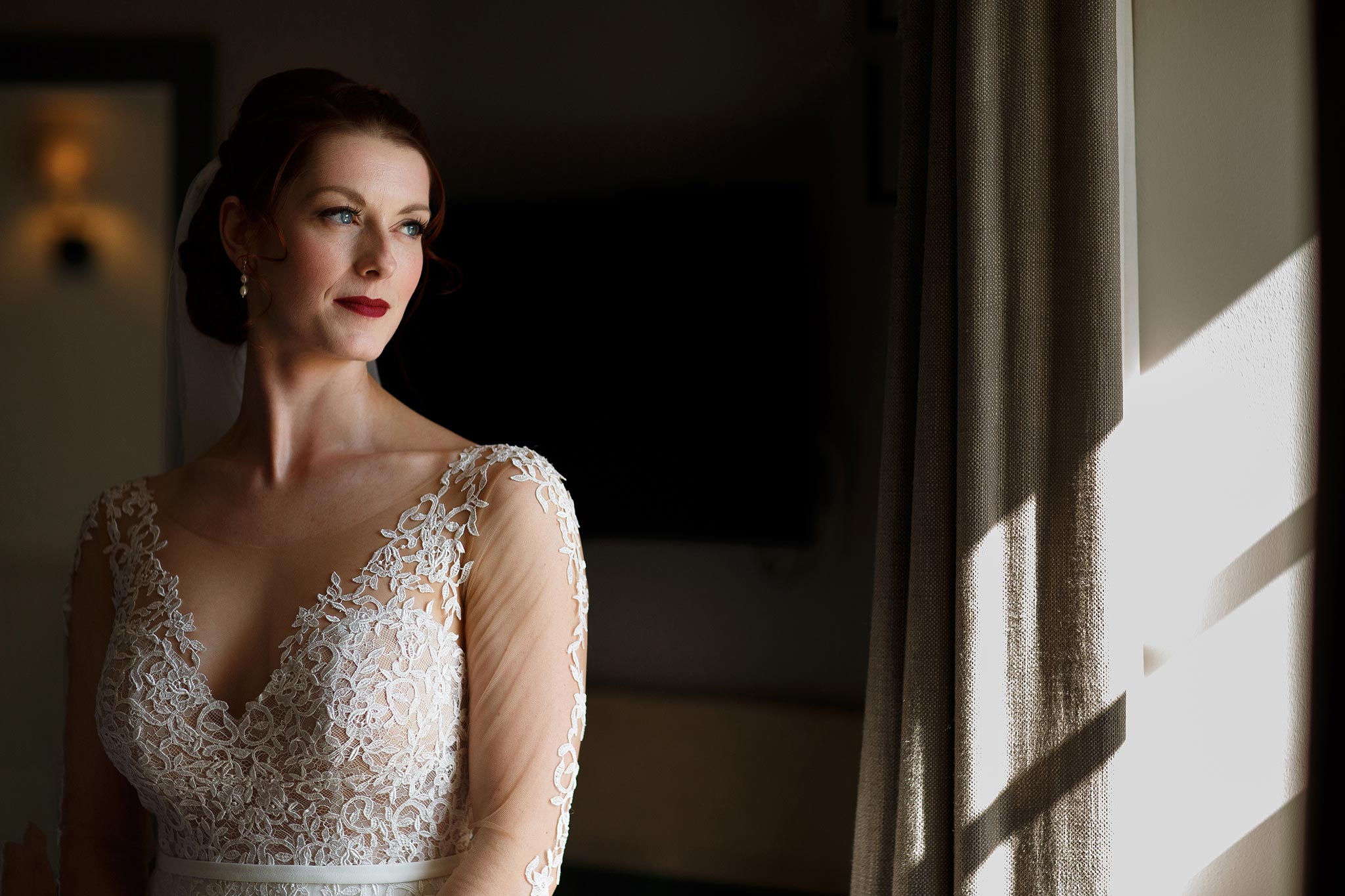 Bride with gorgeous long sleeved dress looking out the window