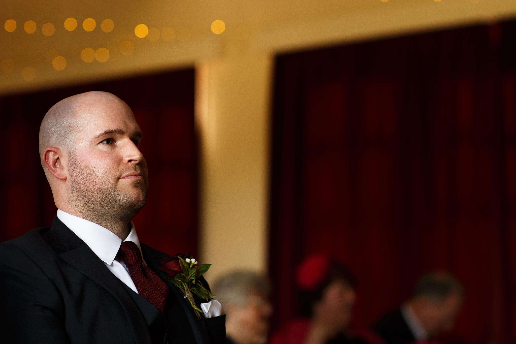Groom waiting nervously at the top of the aisle at village hall wedding