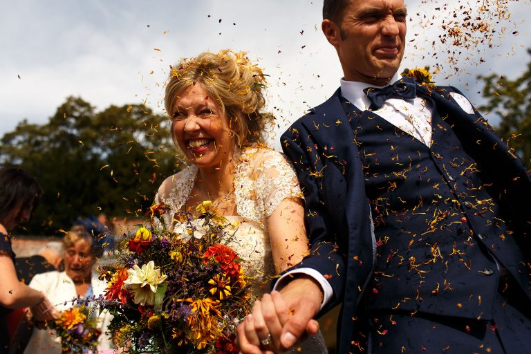 Bride and Groom walking as yellow confetti covers their faces
