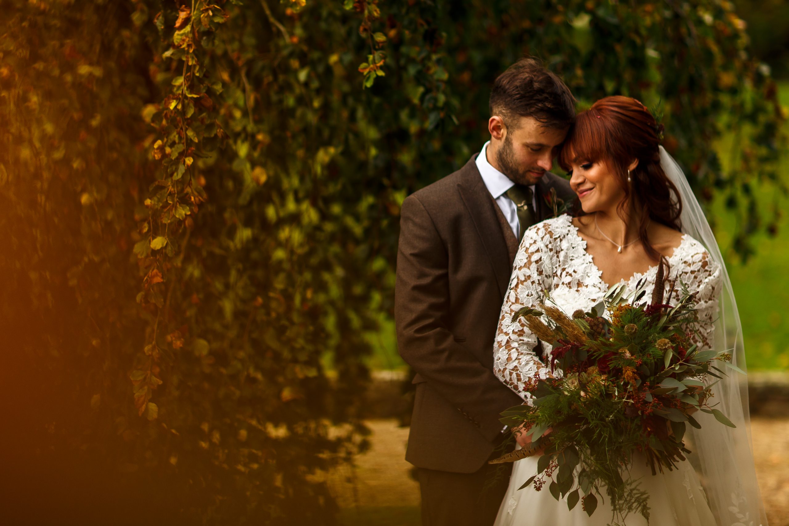 Red haired bride wearing long sleeves snuggled up to her groom