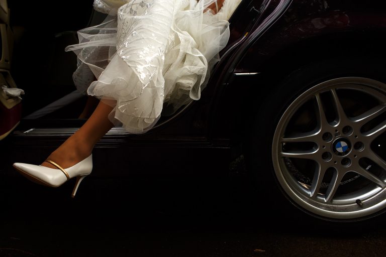 Bride stepping out of black wedding car with just the leg and shoe showing in the image | Nunsmere Hall Wedding Photography