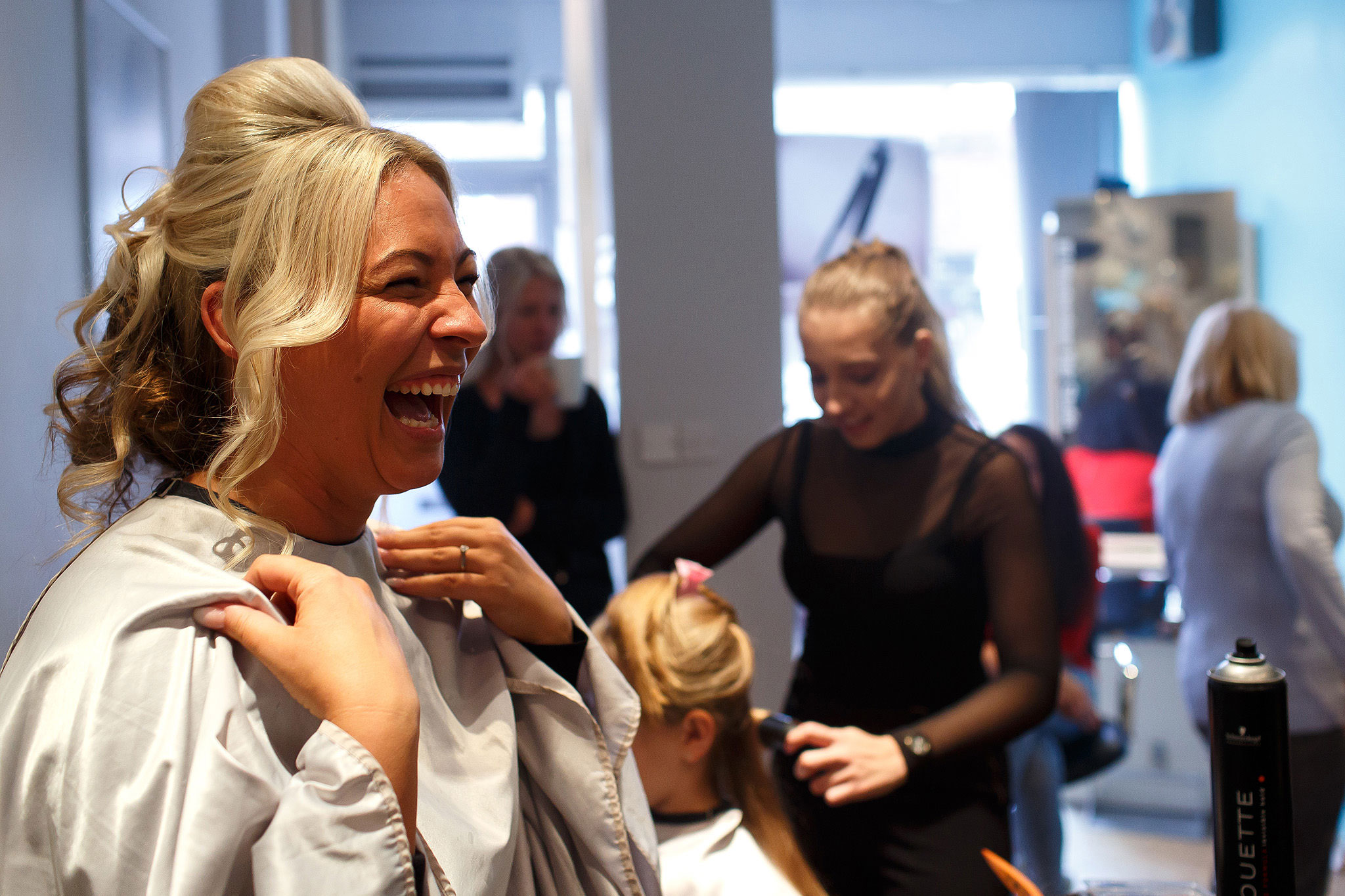 Bride laughing in hair salon on the morning of wedding day 