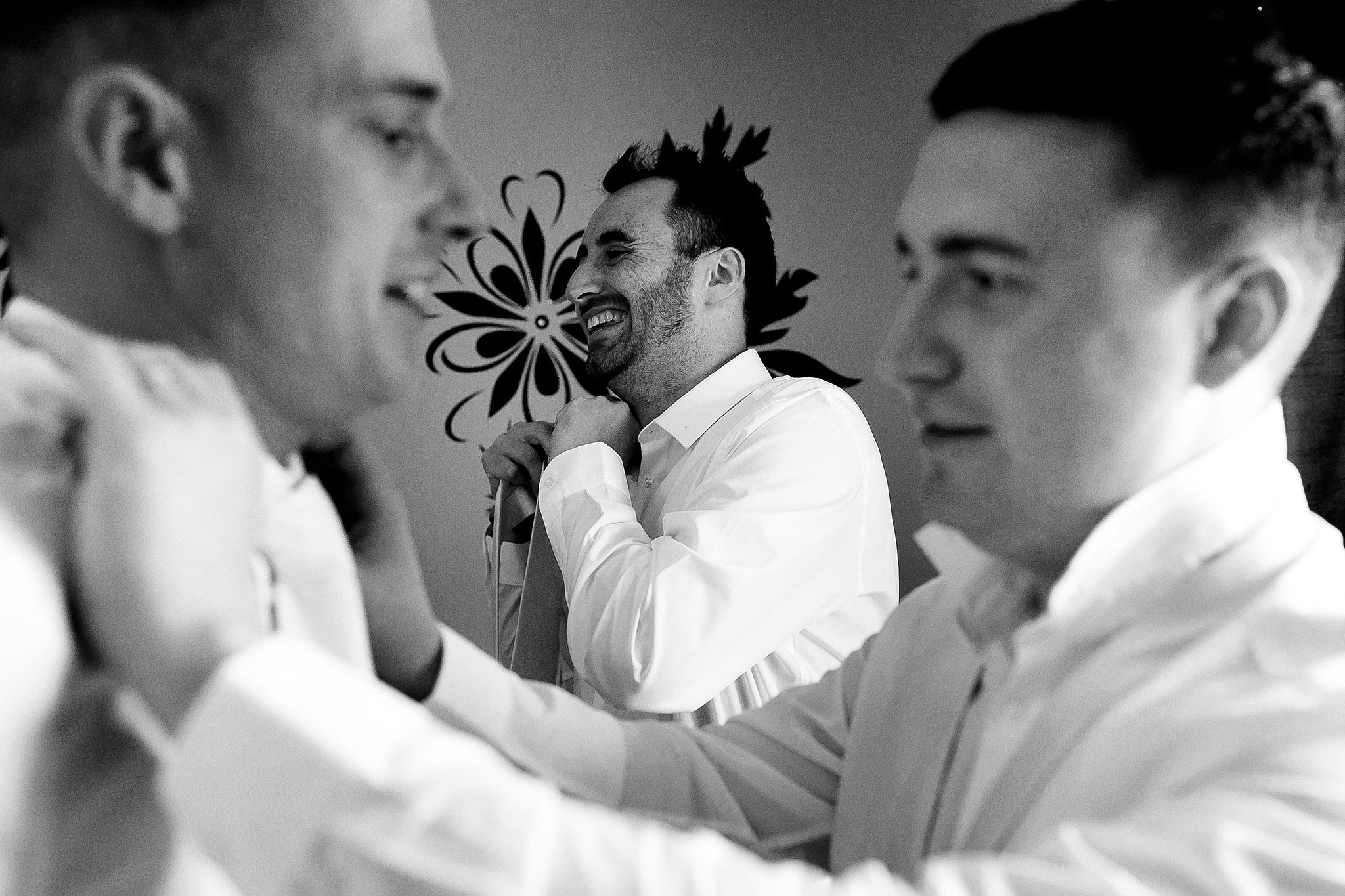 Groomsmen helping each other with ties