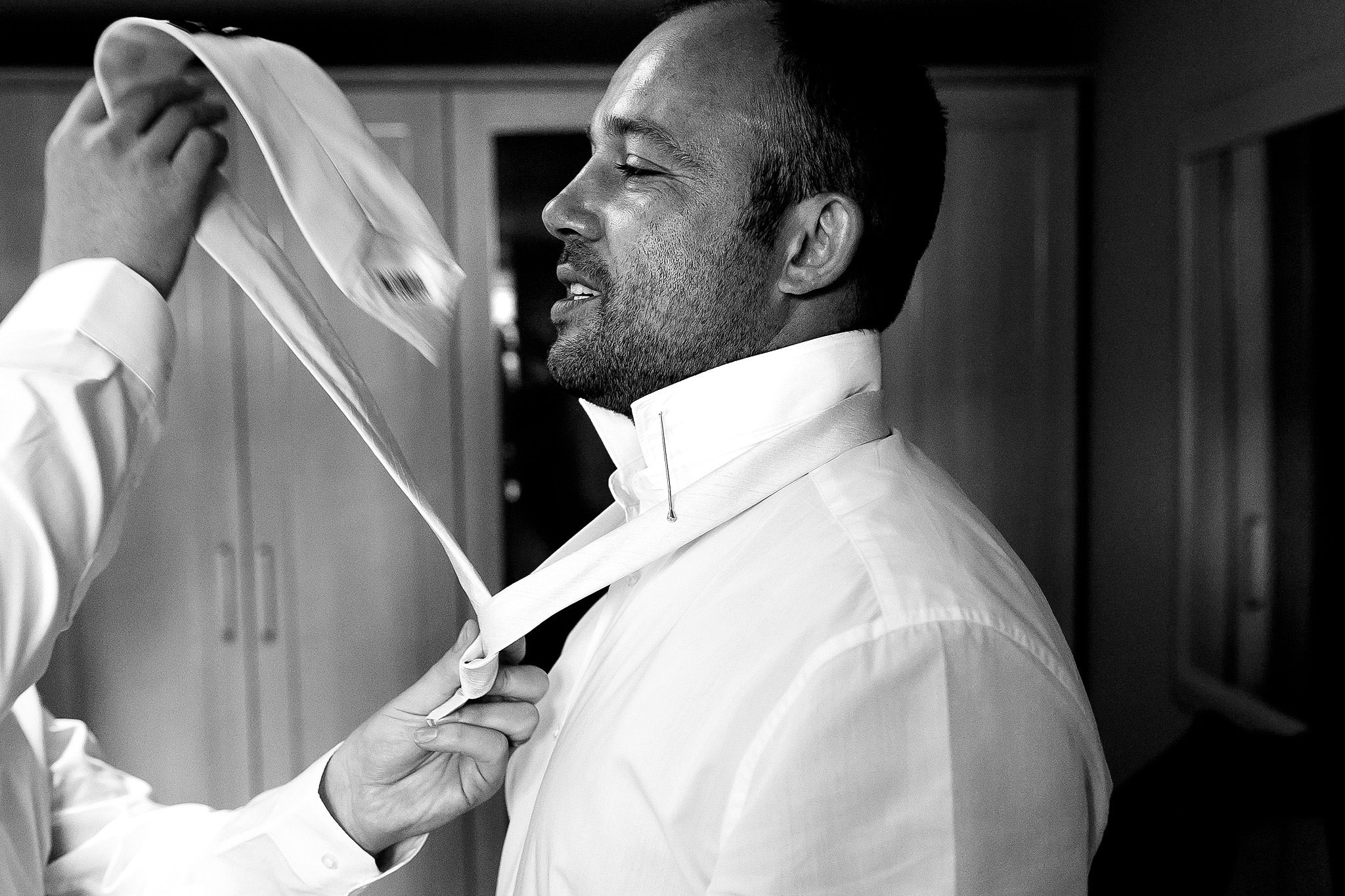 Groomsmen having another usher throw his tie around his neck