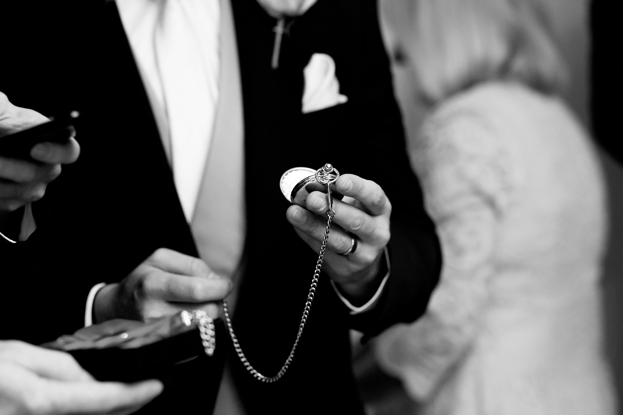 Black and white image of groom holding pocket watch 