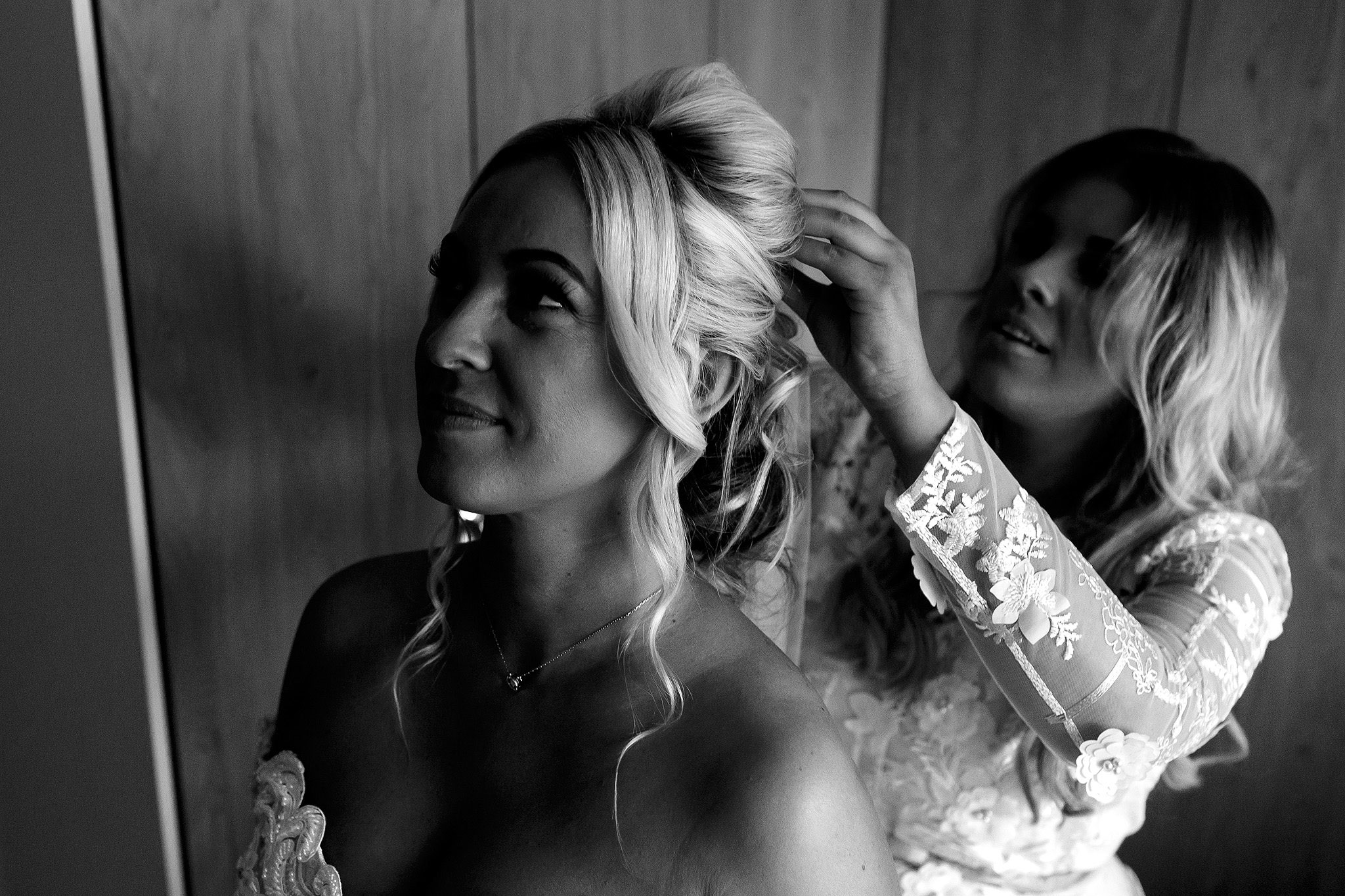 Black and white image with bride having veil put in by bridesmaid