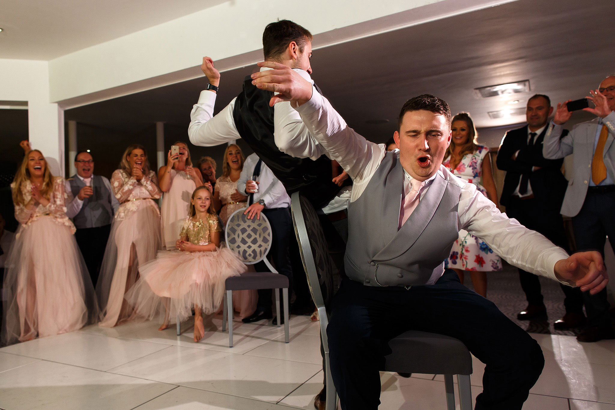 Groomsmen playing Polish drinking games on musical chairs on the dance floor