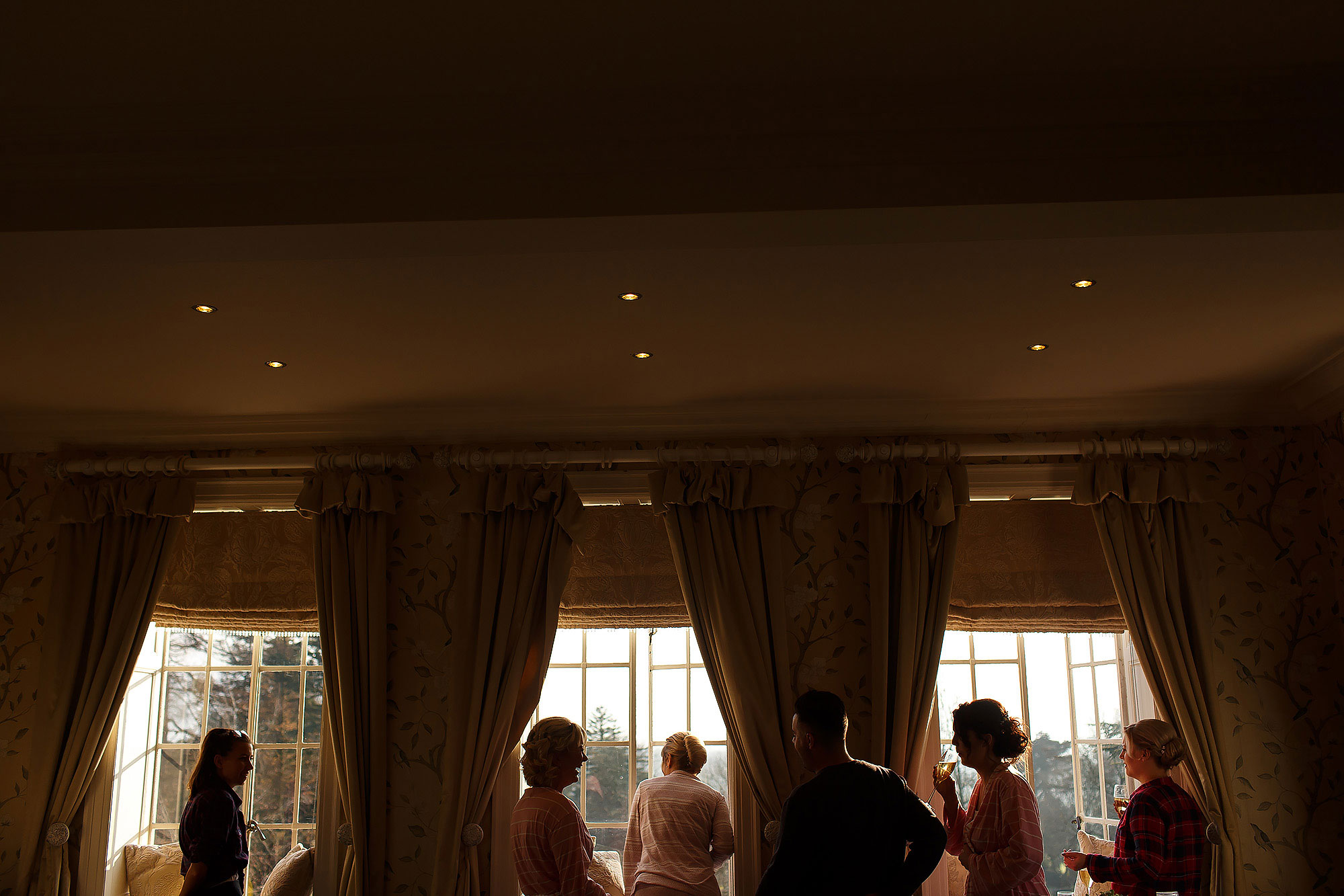 All the bridesmaids looking out the windows of the bridal suite | Eaves Hall wedding photography by Toni Darcy