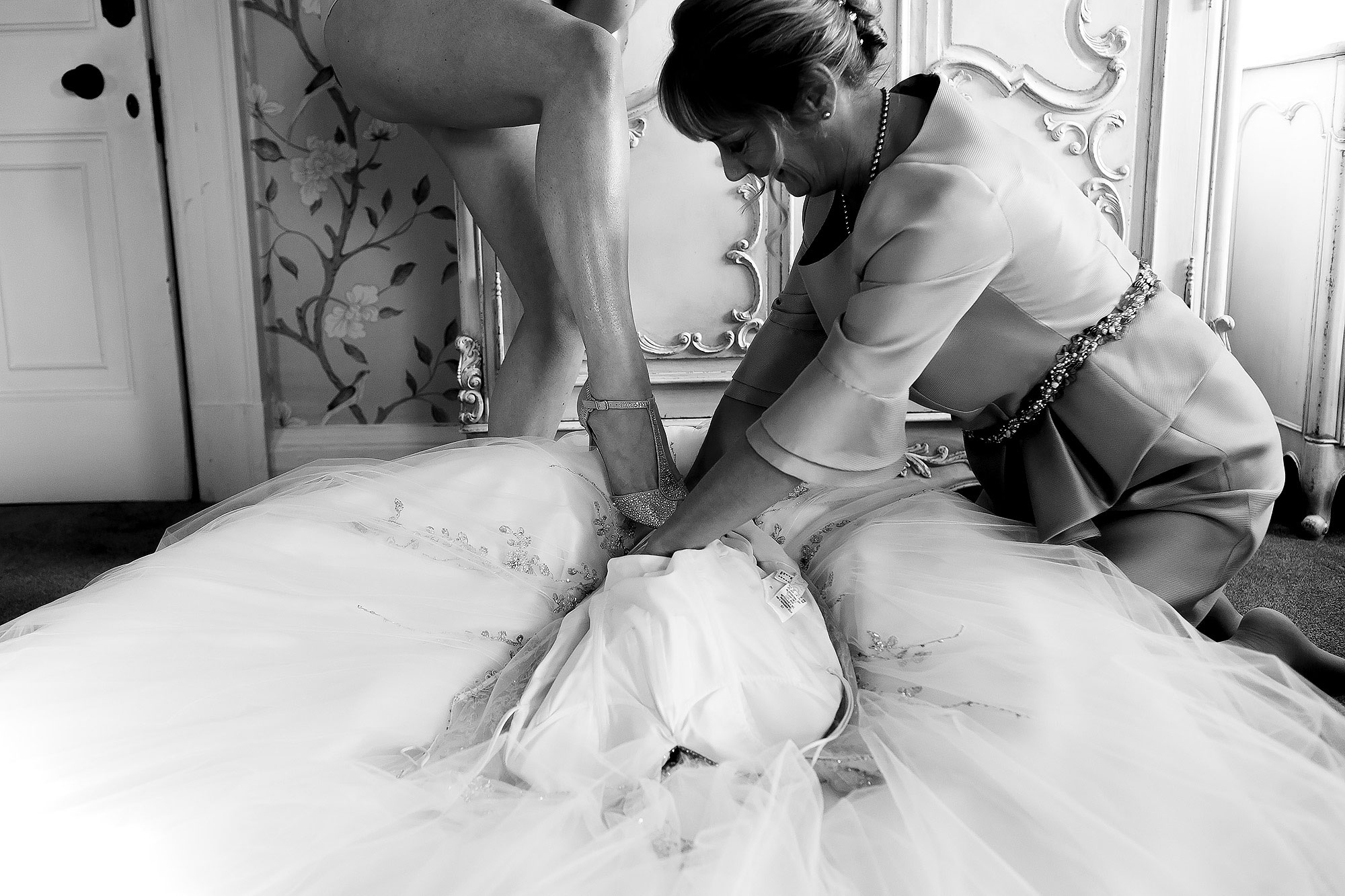 Brides naked leg wearing wedding shoes as she steps into her wedding dress | Eaves Hall wedding photography by Toni Darcy