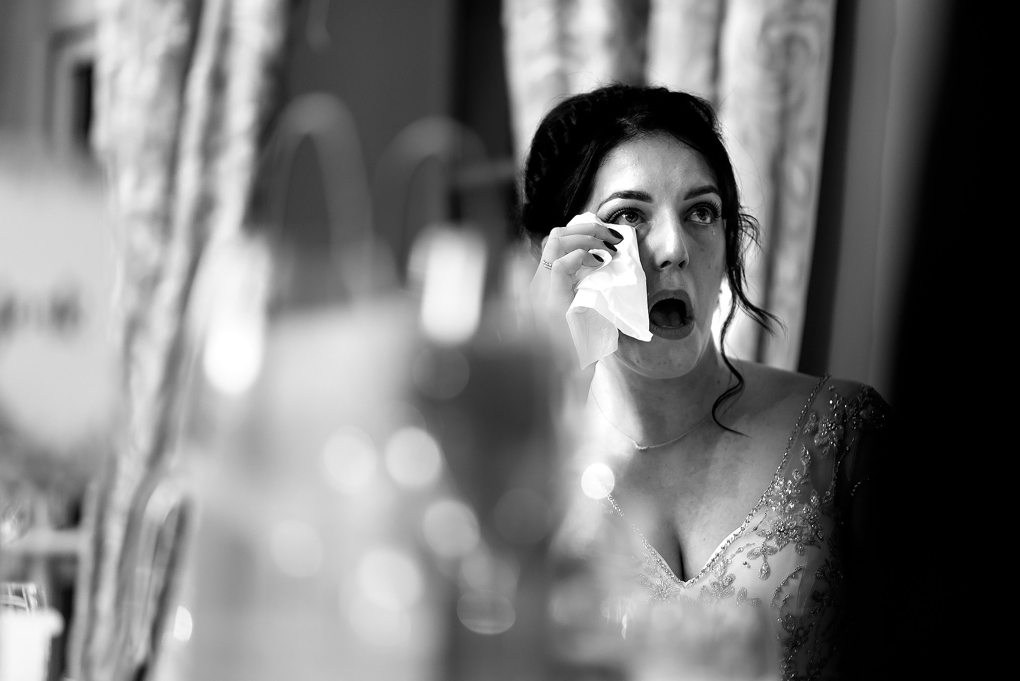 Bride holding a tissue to her eye as she feels emotional during the wedding speeches | Eaves Hall wedding photography by Toni Darcy