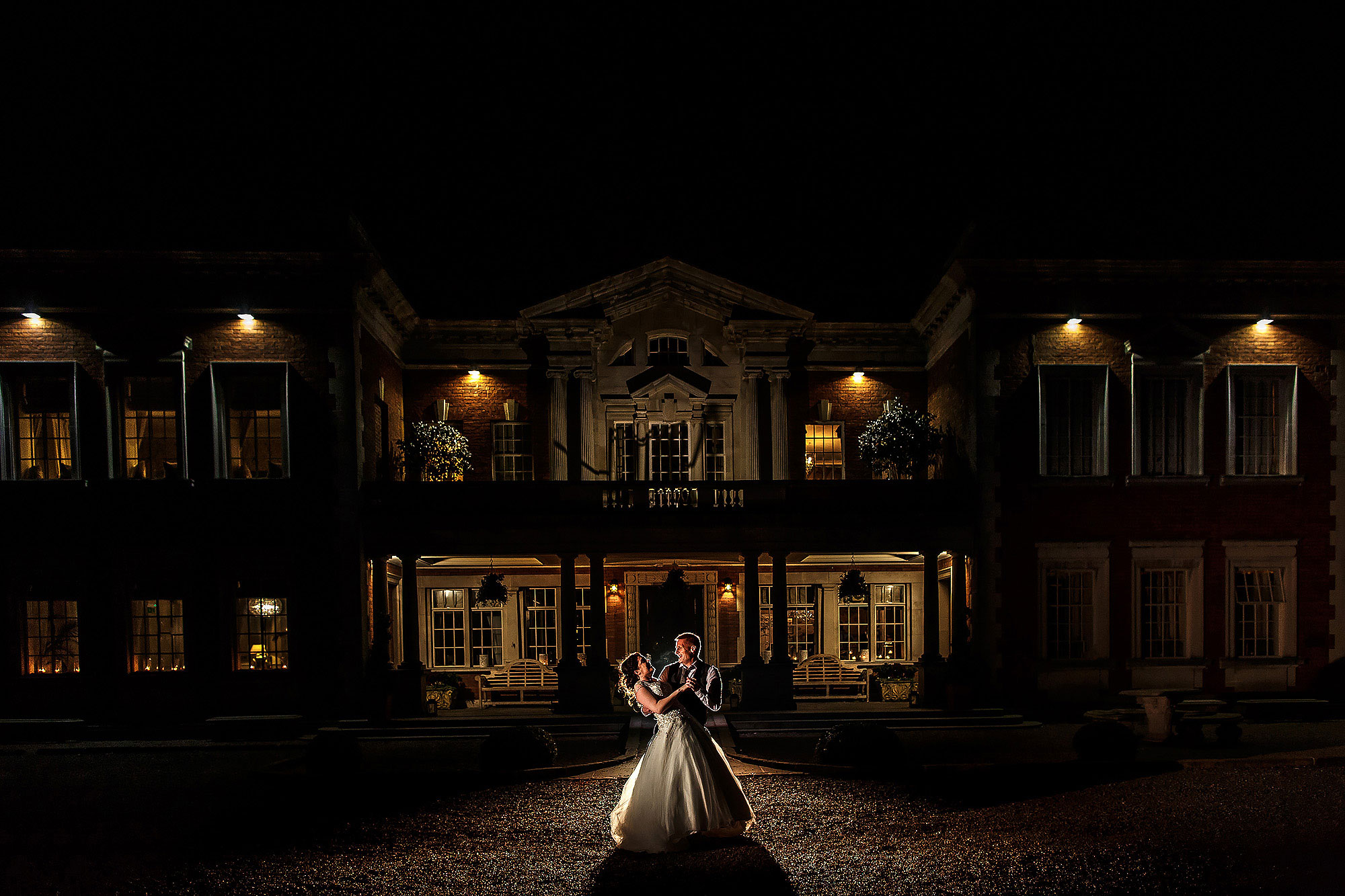 Bride and groom dancing outside Eaves Hall at night with the front of the building lit | Eaves Hall wedding photography by Toni Darcy