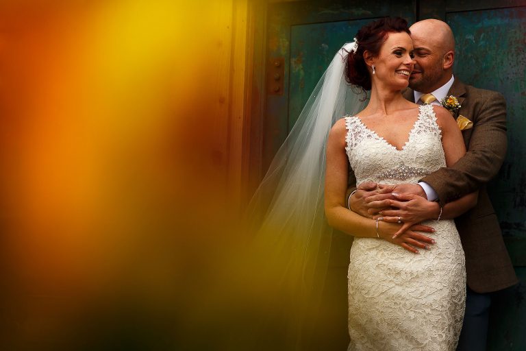 Groom wearing brown tweed suit holding bride wearing lace wedding dress in his arms | Summer wedding at Wellbeing Farm - Toni Darcy Photography